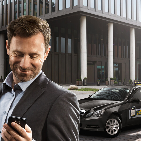 mytaxi Keyvisual schick gekleiderter Mann sieht auf sein Handy und steigt in einen schwarzen myTaxi Mercedes