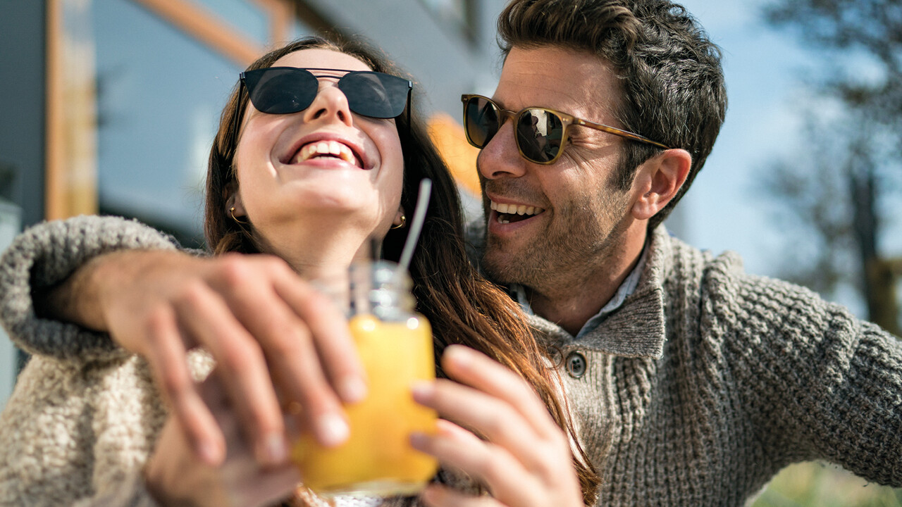 StrandGut Resorts junges Paar mit Sonnenbrillen lacht in herbstlichem Setting