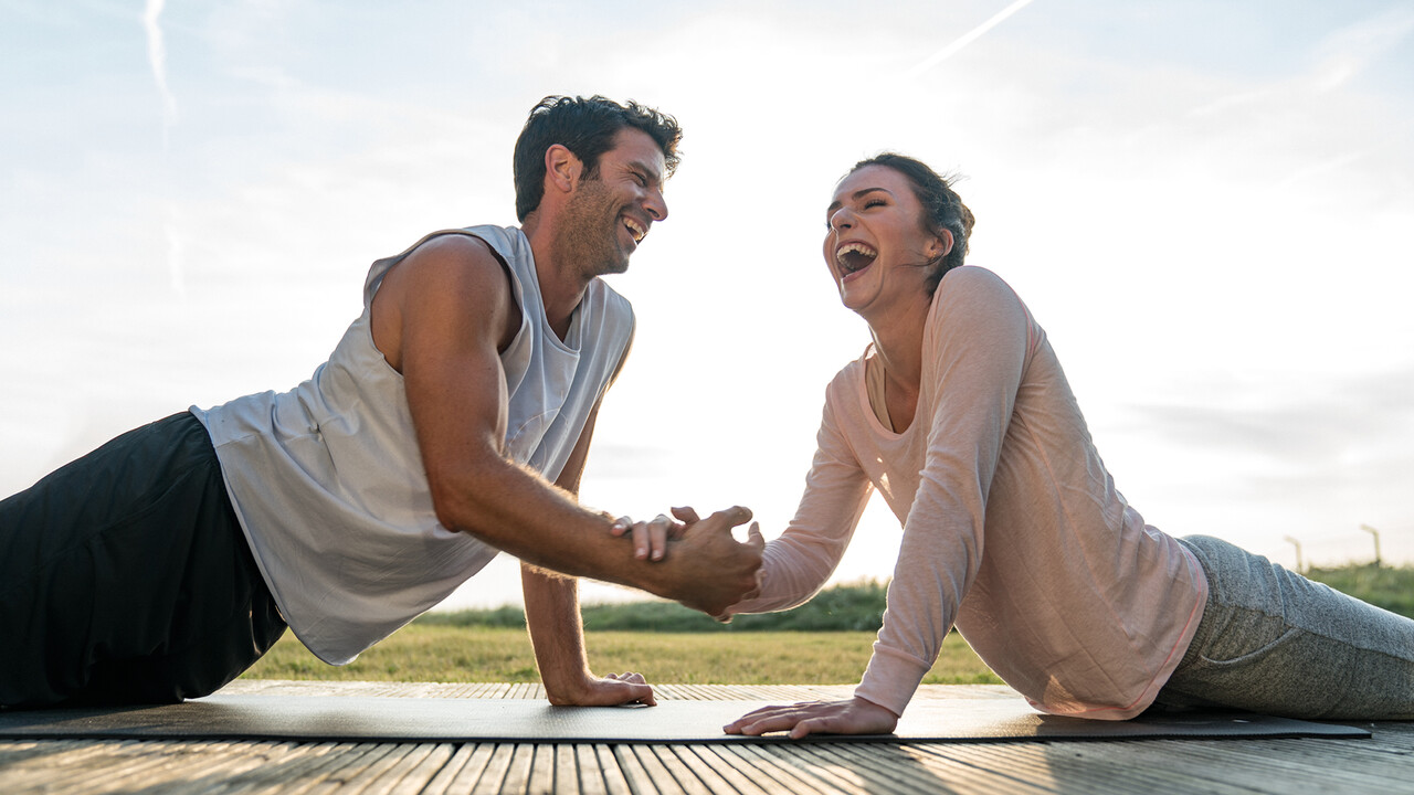 StrandGut Resorts junges Paar liegt in Yoga Pose lachend zusammen auf einer Matte