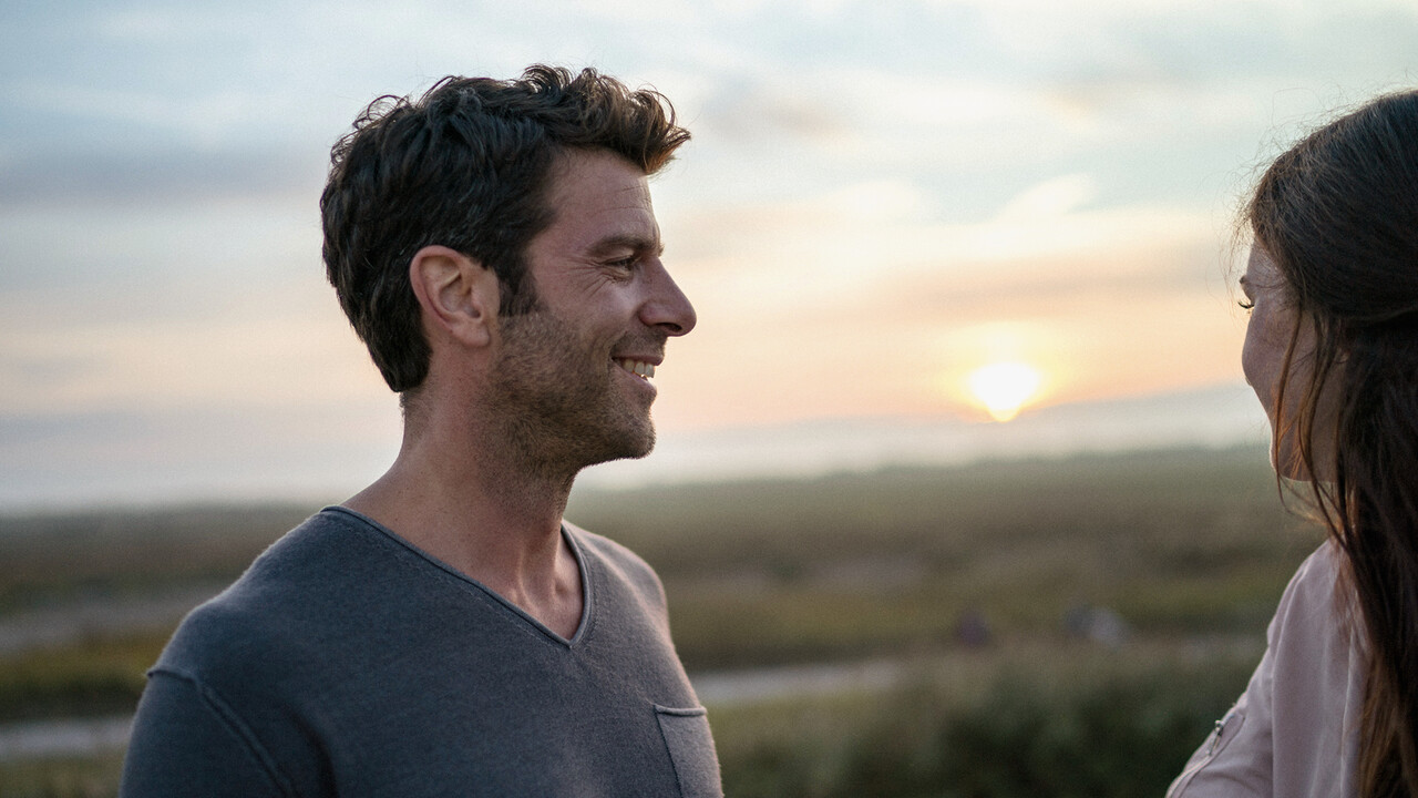 StrandGut Resorts junges Paar lacht sich an in Heidelandschaft in St. Peter-Ording