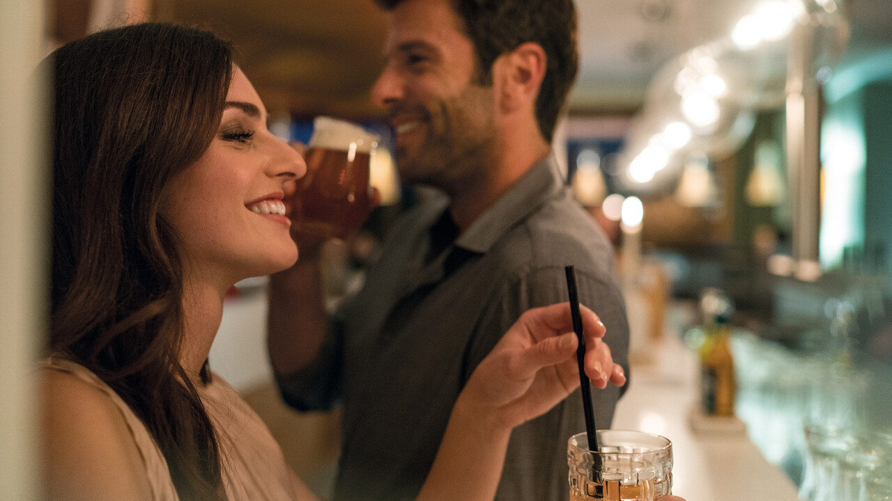 StrandGut Resorts lachendes junges Paar trinkt an einer Bar im StrandGut Resort in St. Peter-Ording