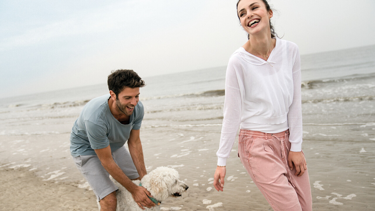 StrandGut Resorts junges Paar spielt mit ihrem Hund am Strand von St. Peter-Ording